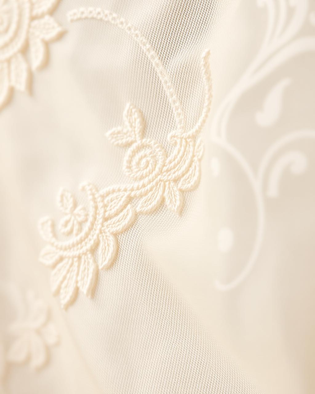 Close detail of white chikankari embroidery on ivory fabric